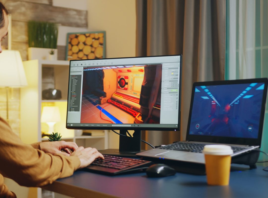 Male game developer typing on keyboard while developing a new level of the game.